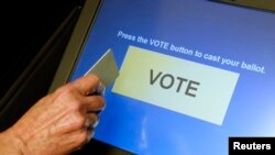 FILE - An elections official demonstrates a touch-screen voting machine at the Fairfax County Governmental Center in Fairfax, Virginia.
