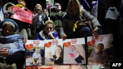 ผู้คนรวมตัวกันด้านหลังโปสเตอร์ตัวประกันชาวอิสราเอล 4 ราย ไม่กี่ชั่วโมงหลังจากกลุ่มฮามาสแห่งปาเลสไตน์ส่งมอบศพ 4 ศพให้กับอิสราเอล ระหว่างพิธีจุดเทียนไว้อาลัยเพื่อเป็นเกียรติแก่พวกเขาในเทลอาวีฟ 20 ก.พ. 2025