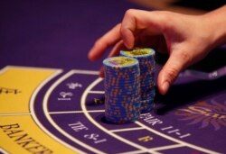 FILE - A croupier counts the chips at a baccarat gaming table inside a casino during the opening day of Sheraton Macao Hotel at the Sands Cotai Central in Macau.