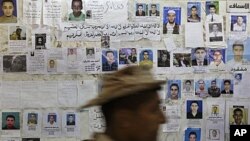 A soldier walks past a wall of posters appealing for information about missing people, at a hospital in Benghazi, Libya, April 17, 2011