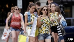 FILE - Consumers hold shopping bags as they walk along Michigan Avenue on July 29, 2016 in Chicago, Illinois. A study reports that the likelihood that young adults will earn more than their parents has plummeted in recent decades.