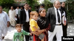FILE - Khalida Bibi, center, sister of Farzana Iqbal, walks with her lawyer as she arrives at a court in Lahore for the trial of those implicated in Iqbal's death, June 2, 2014.