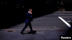 แฟ้มภาพ: นักธุรกิจคุยโทรศัพท์ผ่านไอโฟนของเขา ระหว่างเดินข้ามถนนในย่านธุรกิจใจกลางเมือง ในนครซิดนีย์ ออสเตรเลีย เมื่อ 24 ต.ค. 2027 (รอยเตอร์)