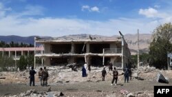 FILE - Afghan security personnel inspect the site of a car bomb blast near the destroyed office building of Afghanistan's intelligence agency in the city of Aybak on July 13, 2020. 