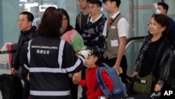 A health surveillance officer uses a device to check the temperatures of passengers near the immigration counters at the Hong Kong International Airport, Jan. 4, 2020.