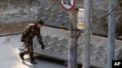 Chinese paramilitary policemen close off a road leading into embassies in the Sanlitun district of Beijing, China, Thursday, Dec. 24, 2015.