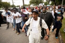 Malik Muhammad, center, joins a group of people marching from the Glynn County Courthouse in downtown to a police station after a rally to protest the shooting of Ahmaud Arbery, Saturday, May 16, 2020, in Brunswick, Ga. (AP Photo/Stephen B. Morton)