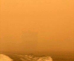 The HMAS Choules appears as a ghostly figure through smoke haze off the coast of Mallacoota, Australia, Jan. 2, 2020. The Australian Defense Force is moving naval assets to Mallacoota on a supply mission. (Australian Defense Force/Reuters)