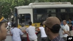 In this image made from video, a protester is dragged to a bus by police officers during an anti-China rally near Chinese Embassy in Hanoi, Vietnam, July 10, 2011