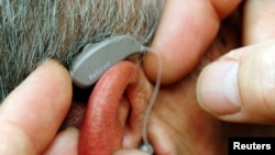 FILE - An employee of GN, the world's fourth largest maker of hearing aids, demonstrates the use of ReSound LiNX in Vienna, Nov. 22, 2013. 