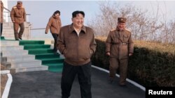 김정은(가운데) 북한 국무위원장이 19일 서해위성발사장에서 신형 중장거리 극초음속 미사일용 다단계 고체연료엔진 지상분출 시험에 참석하며 웃고 있다. 조선중앙통신이 다음날 공개한 사진.