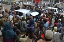 Daily wage workers, jobless due to coronavirus outbreak, rush to a car to receive free food distributed in Quetta, Pakistan, March 23, 2020.