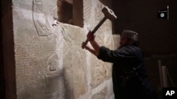 FILE - This image made from video posted on a militant social media account affiliated with the Islamic State group, April 11, 2015, purports to show a militant taking a sledgehammer to an Assyrian relief at the site of the ancient Assyrian city of Nimrud, which dates to the 13th century B.C.