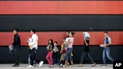 Immigrant families walk along a sidewalk on their way to a respite center after they were processed and released by U.S. Customs and Border Protection, June 24, 2018, in McAllen, Texas. 