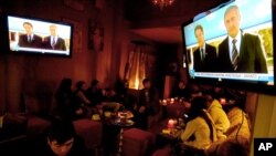 Warga menyaksikan pesan Natal bersama oleh Presiden Siprus Yunani Nicos Anastasiades (kiri) dan pemimpin Siprus Turki Mustafa Akinci di Nicosia, Kamis (24/12).