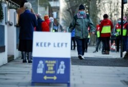 A man wearing a protective mask walks along a queue for vaccinations at Lord's Cricket Ground, amid the COVID-19 outbreak, in London, Britain, Jan. 22, 2021.