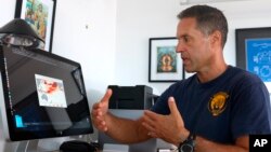FILE - In this Sept. 13, 2019, file photo, Greg Asner, managing director of the Allen Coral Atlas at Arizona State University's Center for Global Discovery and Conservation Science, reviews ocean temperature data at his lab near Captain Cook, Hawaii. 