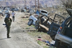 FILE - Fighters of the U.S.-backed Kurdish-led Syrian Democratic Forces (SDF) walk on a road in the fallen Islamic State group's last bastion in the eastern Syrian village of Baghouz after defeating the jihadist group, March 23, 2019.