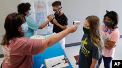 រូបឯកសារ៖ គ្រូៗ ពិនិត្យ​មើល​កំដៅខ្លួន​របស់​សិស្ស​មុន​អនុញ្ញាត​ឲ្យ​ចូល​ជំរំ​រដូវ​ក្តៅ STEM នៅ​វិទ្យាល័យ Wylie ក្នុង​ទីក្រុង Wylie រដ្ឋតិចសាស កាលពី​ថ្ងៃទី១៤ ខែកក្កដា ឆ្នាំ២០២០។