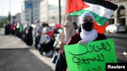 FILE - A protester holds a placard as she takes a part in a human chain during a sit-in against the annexation of parts of the West Bank by Israel, in Amman, Jordan, June 27, 2020. The placard reads: "The Zionist occupation is the root of terrorism." 