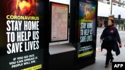 A pedestrian walks past signage about coronavirus = in central London on March 31, 2020.