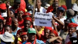 FILE - Protesters hold a placard demanding an end to corruption at a rally in Pretoria, South Africa, Sept. 30, 2015.