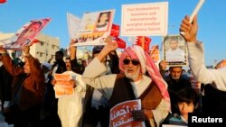 FILE - An anti-government protester holds a sign reading "It Is Impossible For The Bahraini People To Give up On Democracy" as he shouts anti-government slogans during a rally in the village of Bilad al-Qadeem south of Manama, Feb. 11, 2014.
