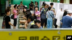 People vote at a polling center for an unofficial referendum on democratic reform in Hong Kong Sunday, June 22, 2014.