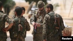 Seorang tentara AS yang bertempur bersama anggota pasukan Demokrasi Suriah (SDF), membawa benderanya saat berkumpul dengan para tentara SDF di Raqqa, Suriah, 27 Mei 2016 (Foto: dok). 