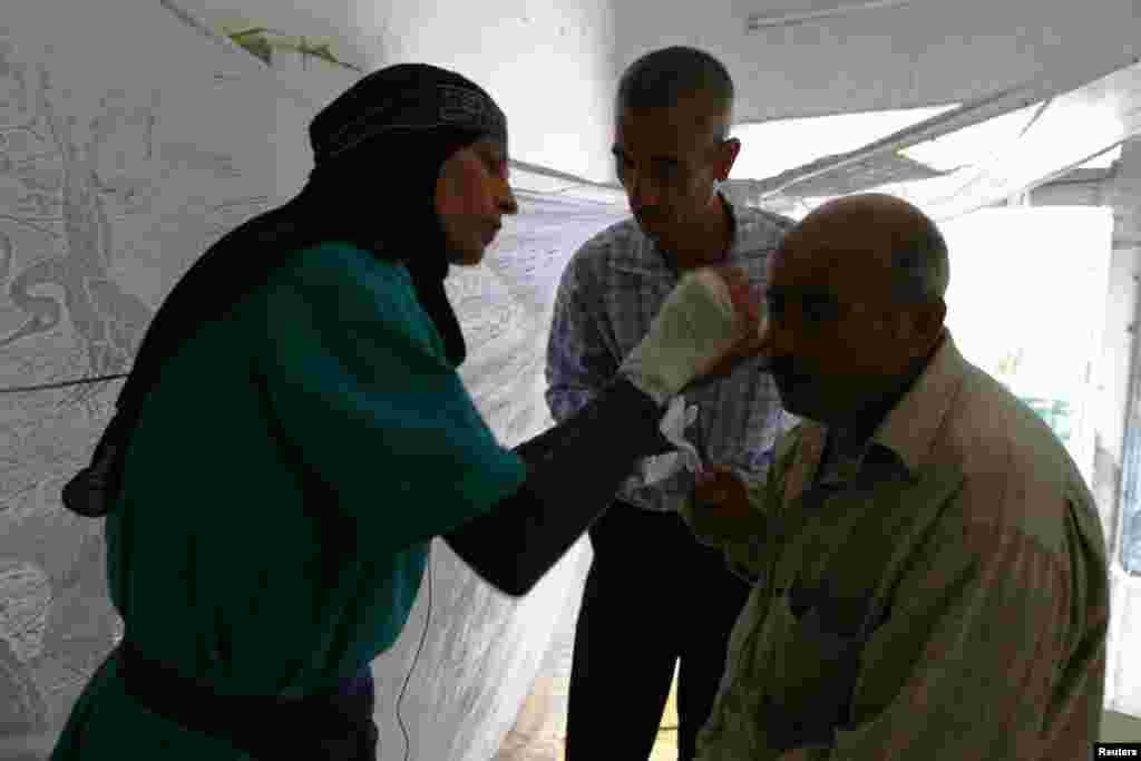 Aisha Masri helps a wounded man at Karaj al-Hajez crossing, a passage way separating Aleppo's rebel-controlled and regime-controlled neighborhoods, Sept. 23, 2013.