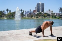 A man exercises shirtless as temperatures rise at MacArthur Park, Tuesday, July 11, 2023, in Los Angeles. Los Angeles is expecting high temperatures between 100 to 110 degrees Fahrenheit later this week according to the National Weather Service. (AP Photo/Marcio Jose Sanchez)