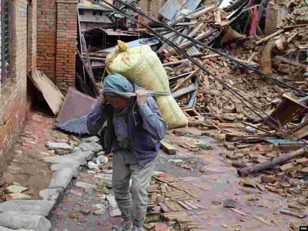 A man carryies approximately 40kg of grain retrieved from his home destroyed by the earthquake, Sankhu, Nepal, April 29, 2015. (Steve Herman/VOA)