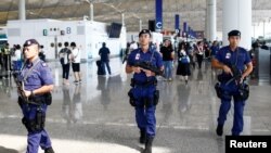 Polisi bersenjata berpatroli di terminal keberangkatan di bandara Hong Kong pasca insiden bentrokan dengan para pengunjuk rasa malam sebelumnya, 14 Agustus 2019.