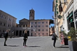 People wear masks as they line up to enter a pharmacy, in Rome, March 16, 2020.