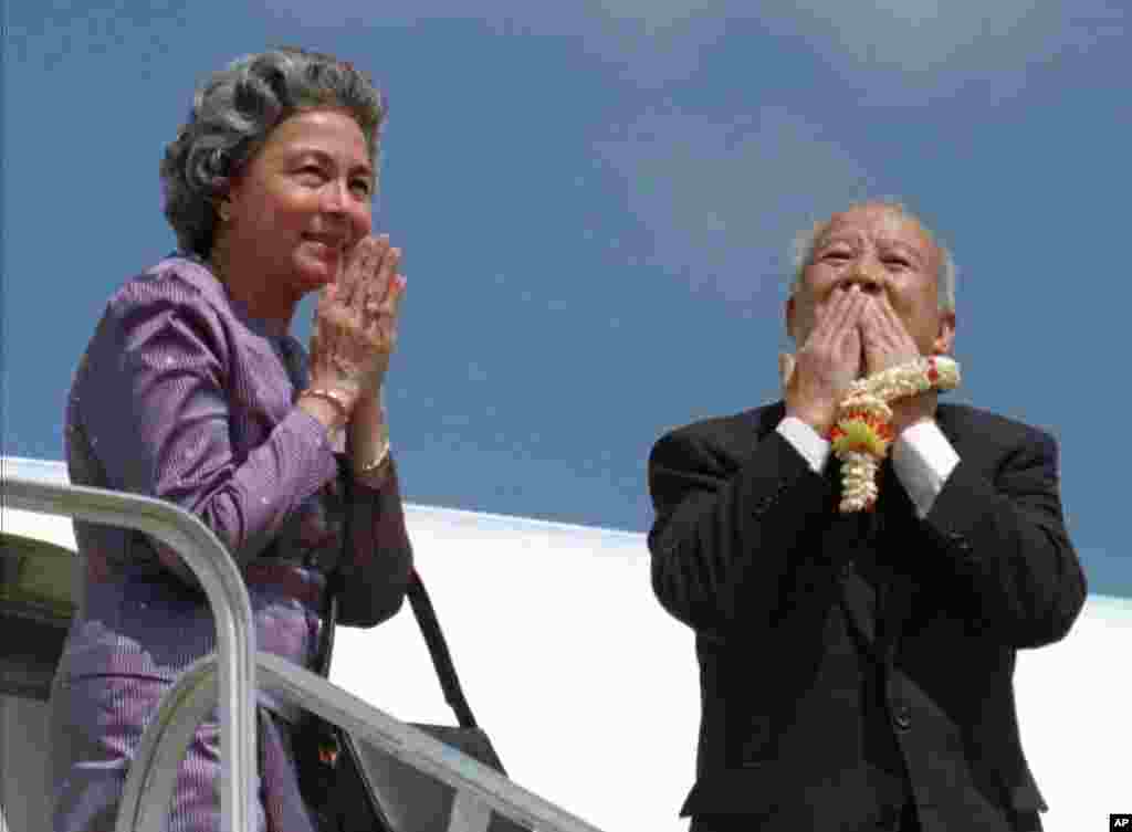 King Sihanouk gives a kiss to say good-bye to well-wishers as Queen Monique prays upon their departure for Beijing at Siem Reap airport, October 25, 1997.