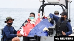 Indonesian Navy personnel carry debris believed to be from the Sriwijaya Air SJ-182 plane, which crashed into the sea, off the Jakarta coast, Indonesia, Jan. 10, 2021. 