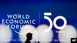 A man silhouettes in front of the logo of the World Economic Forum in Davos, Switzerland, Sunday, Jan. 19, 2020. 
