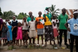 FILE - People hold flags of the ruling APC party as they stand along a road in Bodo, Nigeria, to show support for the start of the government's exercise to clean up pollution in Ogoniland, Nigeria, June 2, 2016.