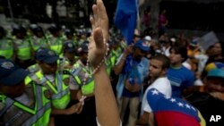 A demonstrator holds up her hand with a rosary entwined, during a protest in Caracas, Venezuela, Jan. 23, 2017. Thousands of opponents of President Nicolas Maduro are marching to demand authorities set a date for overdue regional elections.
