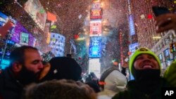 People celebrate as confetti falls down after the countdown to midnight in Times Square, Jan. 1, 2018, in New York. 