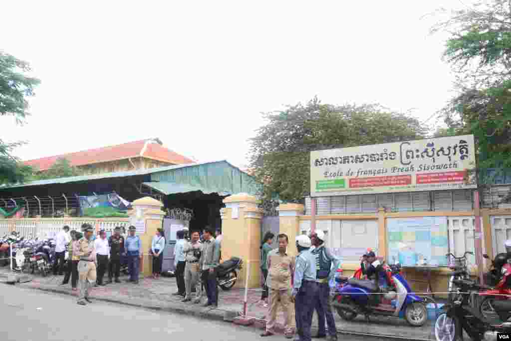 នគរបាលកំពុង​ឈរ​រក្សា​សន្តិសុខ​ ខណៈ​អនុរក្ស​កំពុង​ឈរ​ចាំ​ត្រួត​ពិនិត្យ​បេក្ខជន​​មុន​នឹង​អនុញ្ញាត​ឱ្យ​ចូល​ក្នុង​មណ្ឌល​ប្រលង​វិទ្យាល័យ​ព្រះស៊ីសុវត្ថិ​ កាល​ពី​ថ្ងៃ​ទី​២៤​ សីហា​&nbsp;ឆ្នាំ២០១៥។&nbsp;​(ស៊ូ​ ពិសែន/VOA)