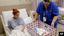 Infant Sleep Recommendations: FILE - In this May 6, 2016, file photo, Keyshla Rivera smiles at her newborn son Jesus as registered nurse Christine Weick demonstrates a baby box before her discharge from Temple University Hospital in Philadelphia on Friday, May 6, 2016. 
