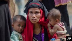 FILE - A Rohingya Muslim woman who crossed over from Myanmar into Bangladesh, holds her son and her daughter, after the government moved them to newly allocated refugee camp areas, near Kutupalong, Bangladesh.