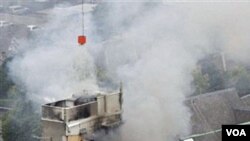 Tim penyelamat berusaha memadamkan kebakaran pada sebuah gedung yang runtuh di pusat kota Christchurch (22/2).