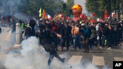 An activist kicks away a tear gas canister during a May Day demonstration in Paris, Wednesday, May 1, 2019.