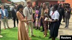 Le prince britannique Harry, duc de Sussex, et son épouse Meghan, duchesse de Sussex, arrivent à la rencontre des étudiants de la Lightway Academy à leur arrivée à Abuja, au Nigeria, le 10 mai 2024.