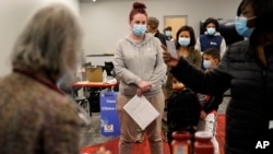 FILE - People stand in line to receive a booster shot of the Pfizer COVID-19 vaccine at a mobile vaccination clinic in Worcester, Massachusetts, Dec. 2, 2021.