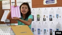 Pekerja pemilu di sebuah TPS di Bangkok menunjukkan kartu suara saat perhitungan pemilu Thailand (7/3).