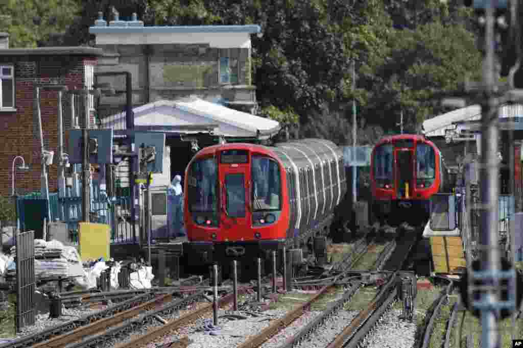 A police forensic officer stands beside the train, at left, where an incident happened, that police say they are investigating as a terrorist attack, at Parsons Green subway station in London, Friday, Sept. 15, 2017. 
