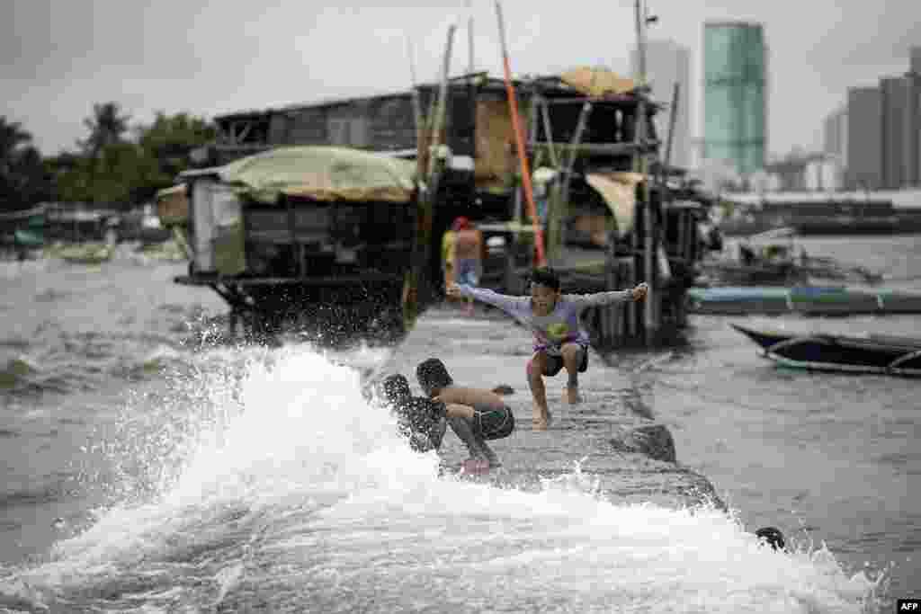 Children living on houses erected on the sea wall of Manila Bay play with waves caused by the Tropical Depression Henry that brought heavy rains in Metro Manila and the northern part of Luzon, Philippines.